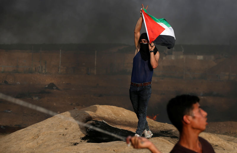 © Reuters. Manifestante segura bandeira palestina em protesto na fronteira Israel-Gaza