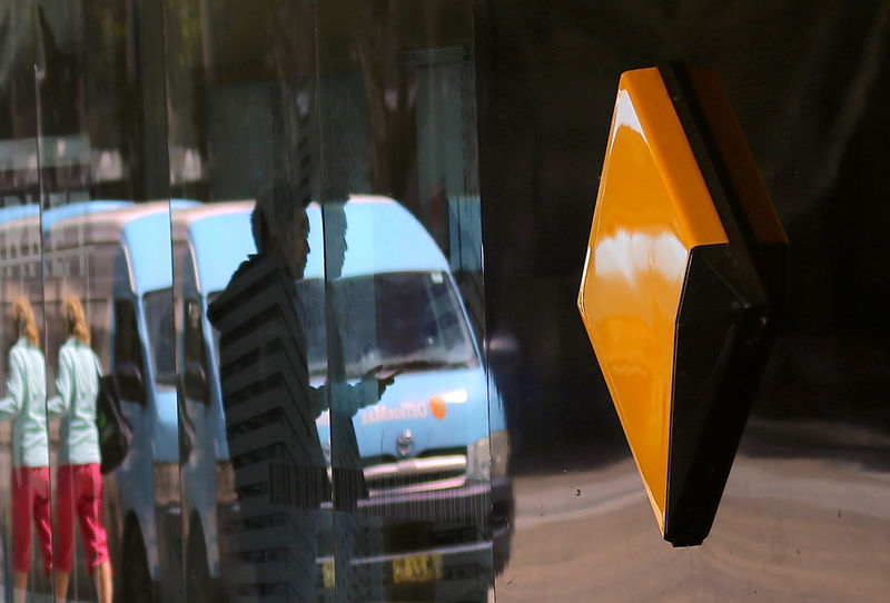 © Reuters. FILE PHOTO: Pedestrians are reflected in the window of a branch of the Commonwealth Bank of Australia (CBA), Australia's biggest bank by market value, in Sydney