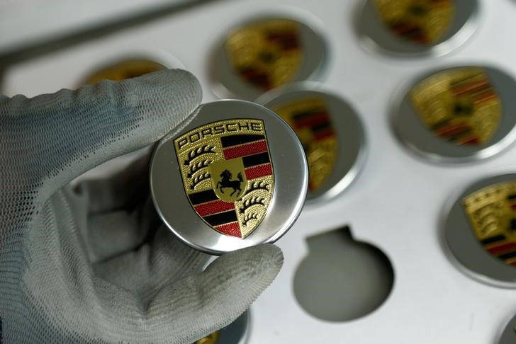 © Reuters. An employee of German car manufacturer Porsche displays a badge depicting a Porsche logo at the Porsche factory in Stuttgart-Zuffenhausen
