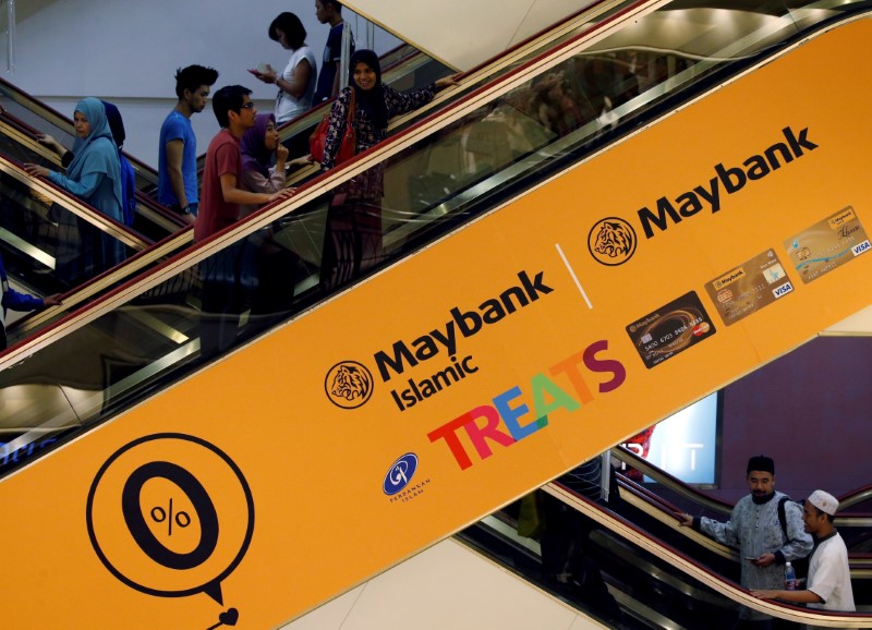 © Reuters. FILE PHOTO: People take an escalator with Maybank advertisement at a a mall in Kuala Lumpur