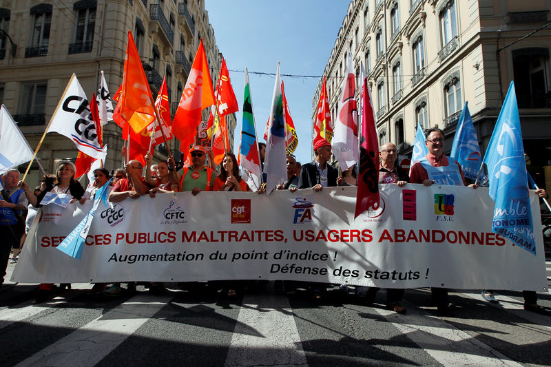 © Reuters. French civil servants carry labour union flags as they march behind a banner during a national day of strikes by public sector workers, in Lyon
