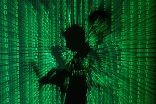 © Reuters. FILE PHOTO: An illustration picture shows projection of binary code on man holding aptop computer in Warsaw