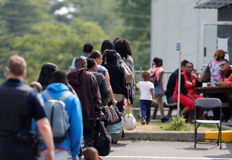 © Reuters. FILE PHOTO: A group of asylum seekers wait to be processed after being escorted from their tent encampment to the Canada Border Services in Lacolle