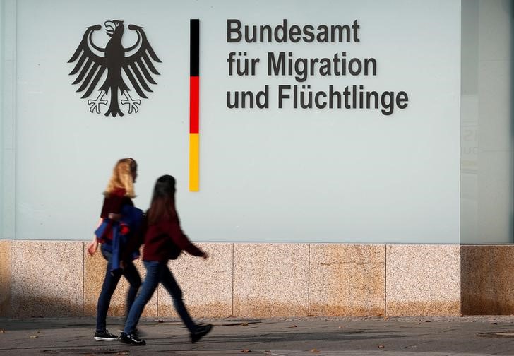 © Reuters. People walk in front of an office building of the Federal Office for Migration and Refugees in Berlin
