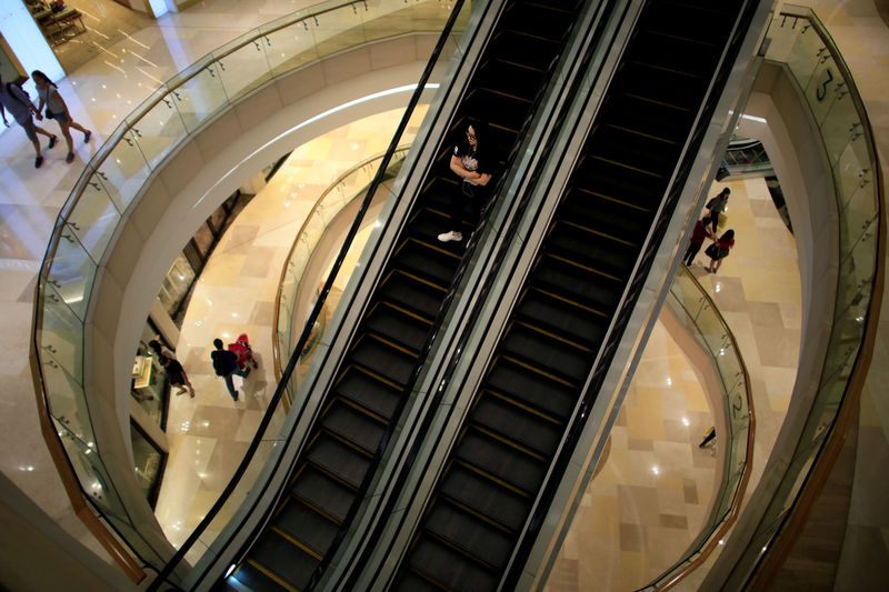 © Reuters. FILE PHOTO: A woman rides down an escalator at a shopping mall in Singapore