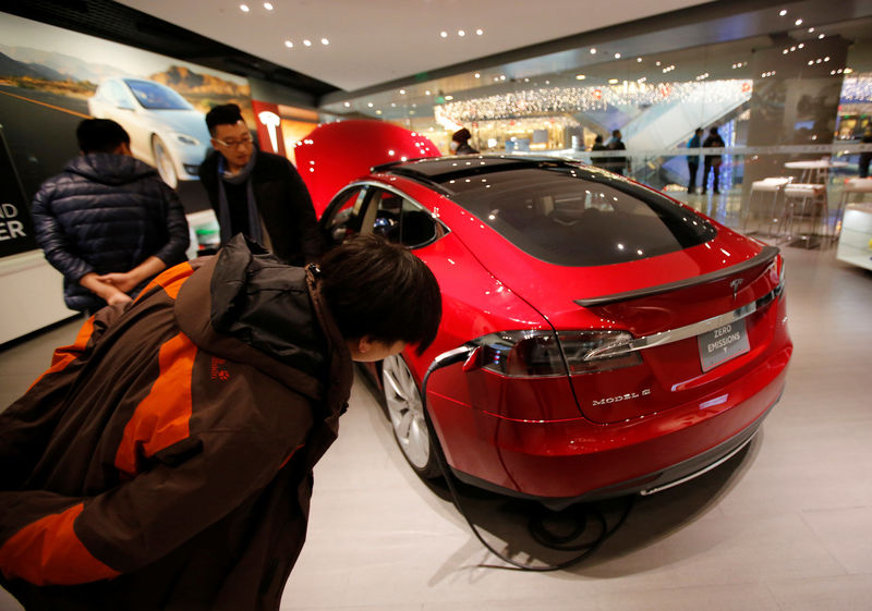 © Reuters. FILE PHOTO: Visitors look at a Tesla Model S car at a Tesla showroom in Beijing