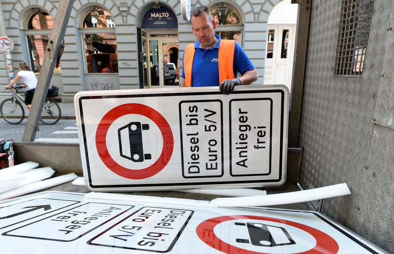 © Reuters. A worker picks up a traffic sign which bans diesel cars in downtown Hamburg
