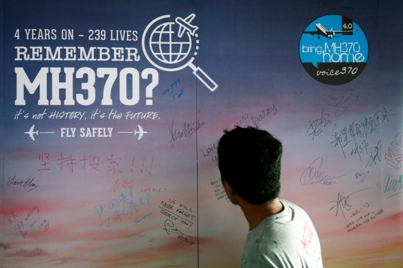 © Reuters. Homem observa painel com mensagem para passageiros desaparecidos no voo MH370, em Kuala Lumpur