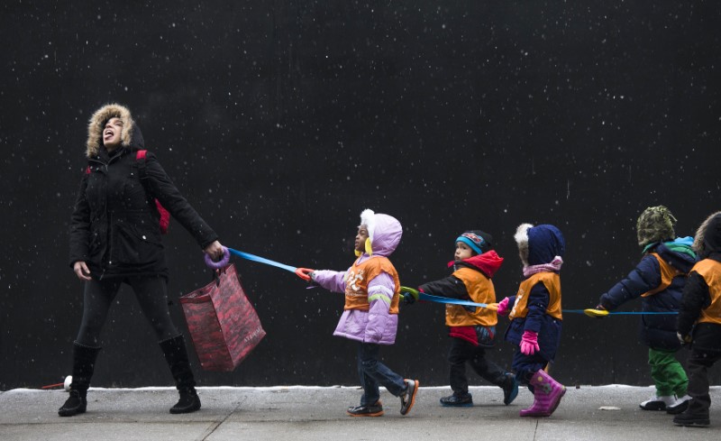 © Reuters. A schoolteacher, who wished to stay unidentified, attempts to catch snowflakes while leading her students to a library from school in the Harlem neighborhood of New York