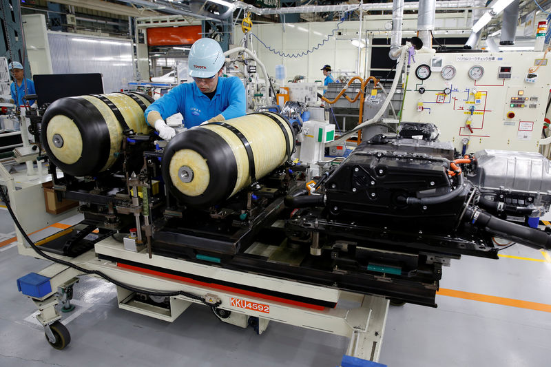 © Reuters. An employee of Toyota Motor Corp. works next to the unit of fuel cell stack and hydrogen tanks of a Mirai fuel cell vehicle in Toyota