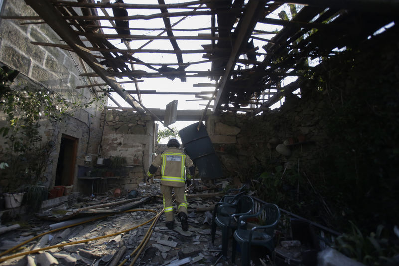 © Reuters. Un bombero camina por una casa en ruinas tras una explosion de un almacén pirotécnico en Tui