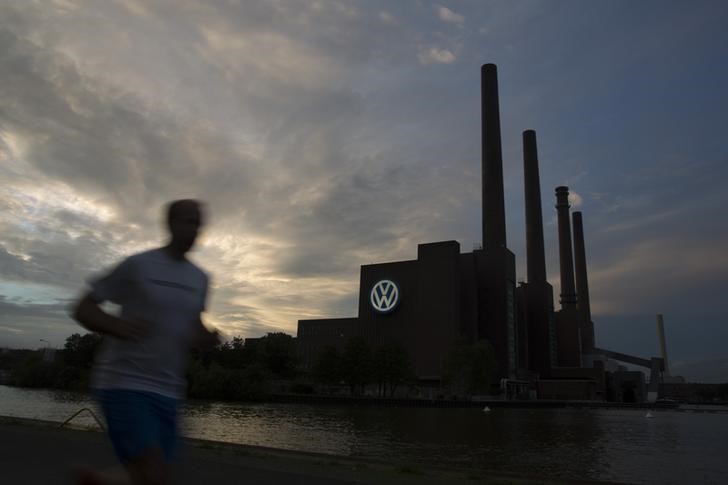 © Reuters. Jogger runs along bank of Midland Canal in front of Volkswagen power plant in Wolfsburg
