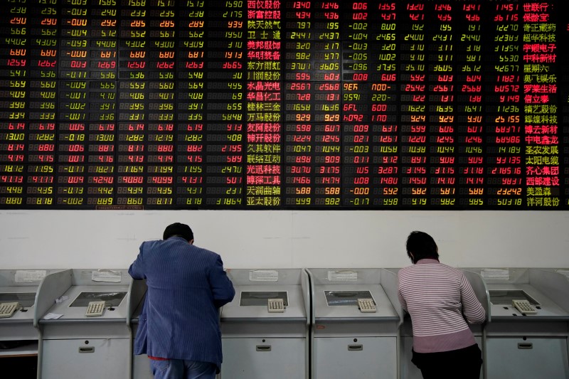 © Reuters. Investidores observam dados de ações em casa de corretagem em Xangai, na China