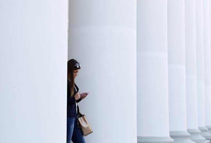 © Reuters. Женщина пользуется мобильным телефоном у здания университета в Казани
