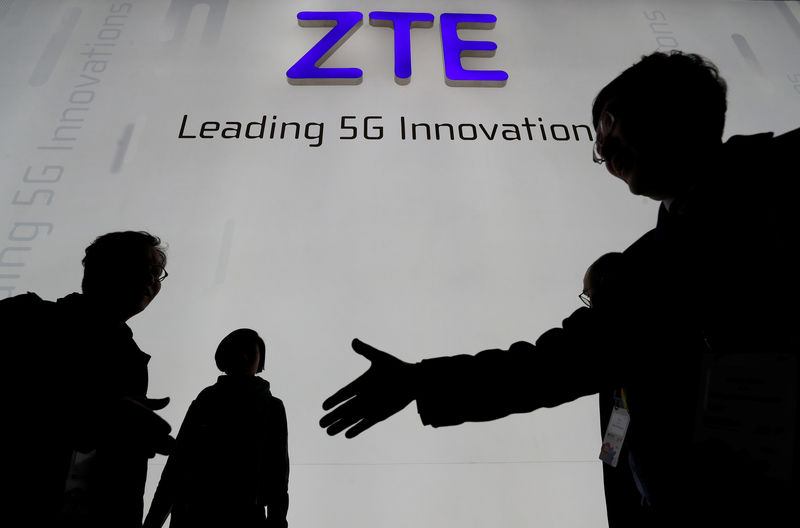 © Reuters. FILE PHOTO - Visitors pass in front of the ZTE booth at the Mobile World Congress in Barcelona