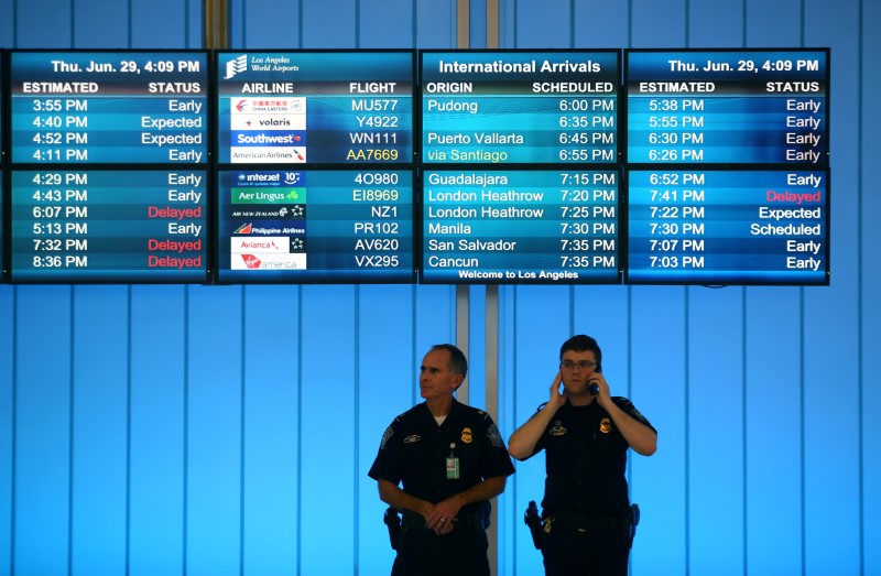 © Reuters. U.S. Customs and Immigration officers keep watch at the arrivals level at Los Angeles International Airport in Los Angeles, California