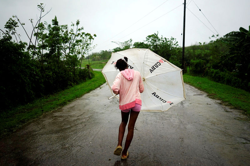 © Reuters. Dalma Samora walks against the winds of Subtropical Storm Alberto as it passes by the west coast of Cuba, in La Palma, Cuba