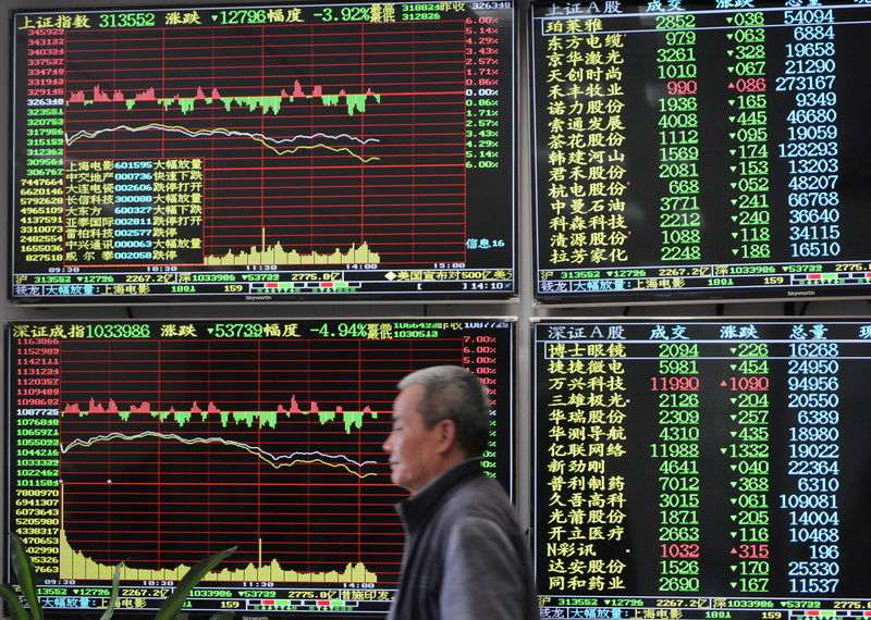 © Reuters. FILE PHOTO: Man is seen against an electronic board showing stock information at a brokerage house in Jiujiang, Jiangxi