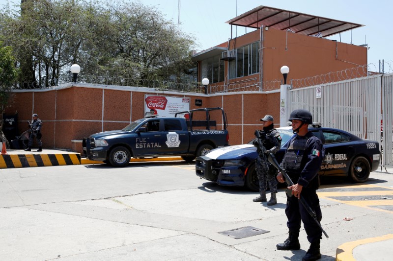 © Reuters. FILE PHOTO: Police officers guard the entrance of the Coca-Cola FEMSA distribution plant after it closes down due to the issues of security and violence during the campaign rally of Independent presidential candidate Margarita Zavala in Ciudad Altamirano