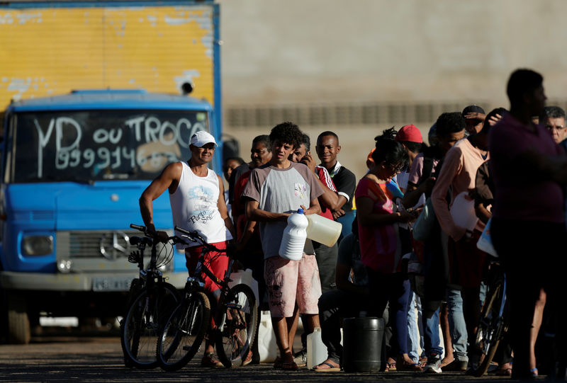 © Reuters. People wait in line to fill their canisters with fuel at a gas station in the outskirts of Brasilia