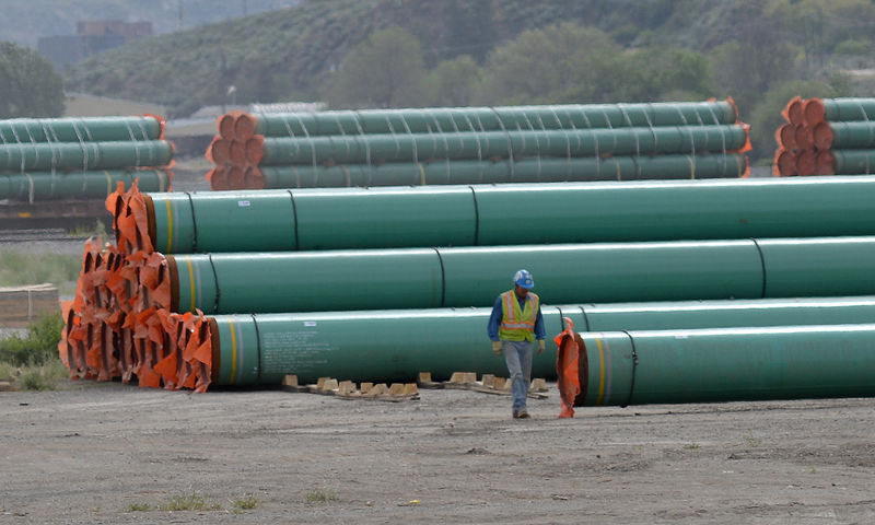 © Reuters. A workman walks past steel pipe to be used in the pipeline construction of the Trans Mountain Expansion Project at a stockpile site in Kamloops