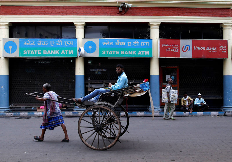 © Reuters. A rickshaw puller transports a passenger as he rides past closed automated teller machines (ATMs) during a 48-hour long strike, in Kolkata