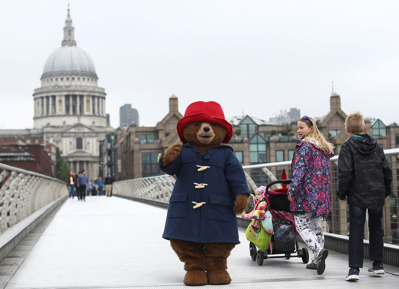 © Reuters. A performer wearing a Paddington Bear costume poses for photographers in front of St Paul's Cathedral in London