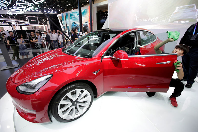 © Reuters. FILE PHOTO: A man cleans a Tesla Model 3 car during a media preview at the Auto China 2018 motor show in Beijing