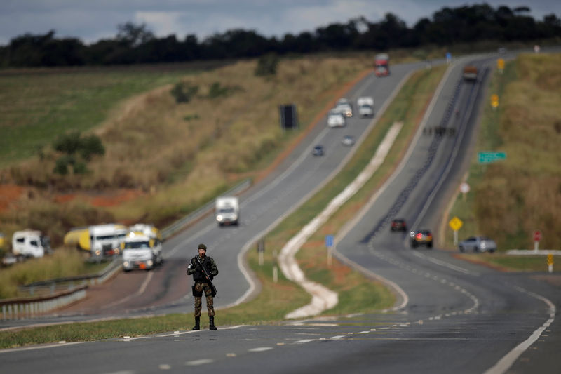 © Reuters. Army officers escort trucks transporting cooking gas and aviation gasoline to fuel airplanes at International Brasilia Airport, on the BR-040 highway in Luziania