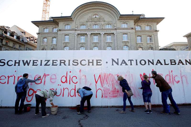 © Reuters. FILE PHOTO: Members of the sovereign money initiative, a referendum campaign that would abolish traditional bank lending and allow only money created by the central bank, clean up after spraying a slogan on the Swiss National Bank (SNB) in Bern