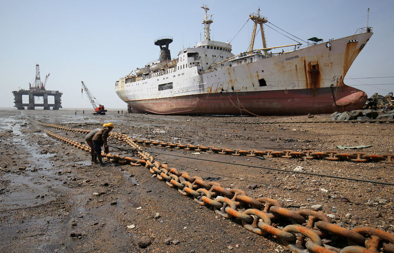 © Reuters. FILE PHOTO: Workers pull a rope tied to a decommissioned oil rig to dismantle it at the Alang shipyard