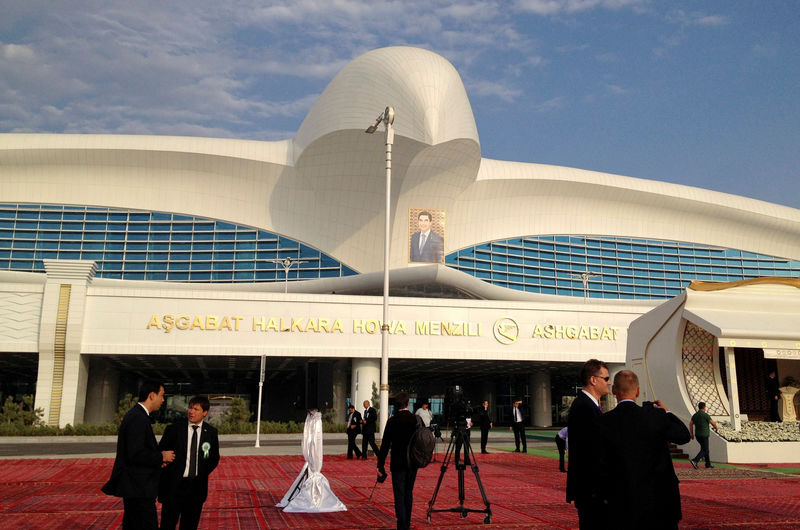© Reuters. FILE PHOTO: People stay in front of the terminal of the newly built airport with a portrait of Turkmen President Kurbanguly Berdymukhamedov seen in the background during its official opening in  Ashgabat, Turkmenistan