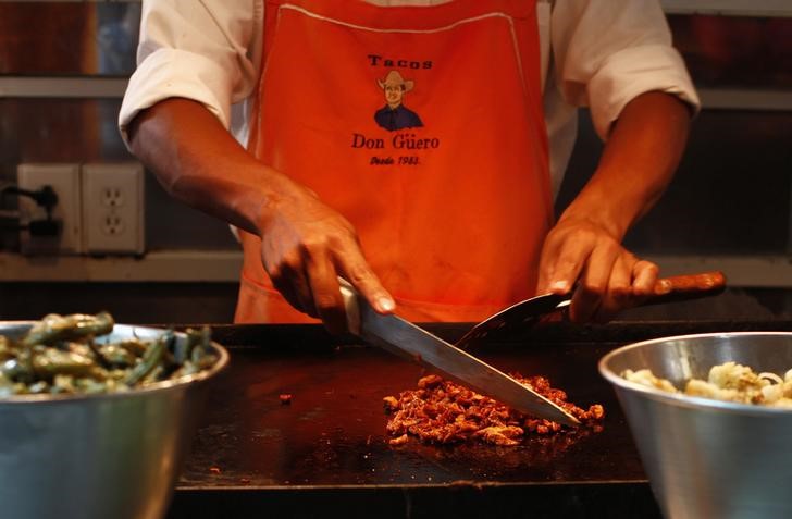 © Reuters. Повар режет свинину для тако в Мехико