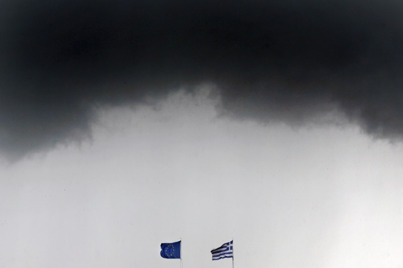 © Reuters. FILE PHOTO: A Greek national flag and an EU flag flutter under storm clouds in Athens