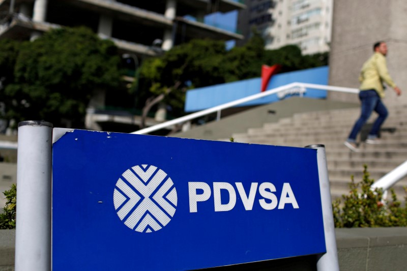 © Reuters. FILE PHOTO: A man walks past a gas station with the logos of the Venezuelan state oil company PDVSA in Caracas