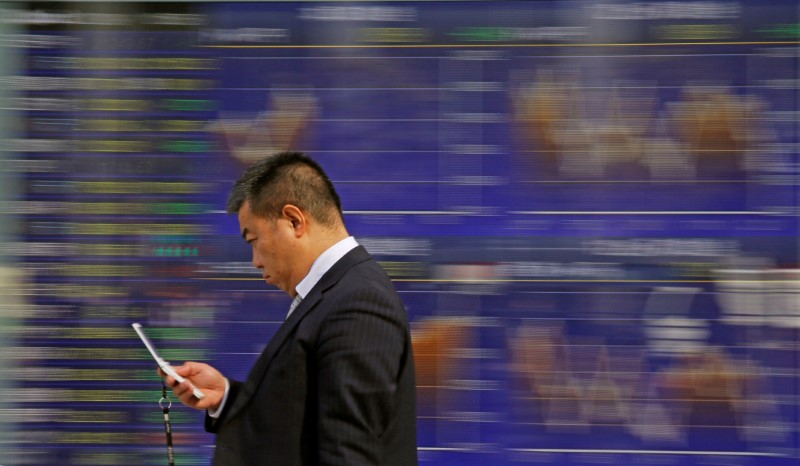 © Reuters. Tokyo, un passante davanti al tabellone elettronico di un brokerage con l'andamento di borsa