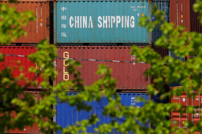 © Reuters. Worker gestures as a crane lifts goods onto a cargo ship, at a port in Lianyungang