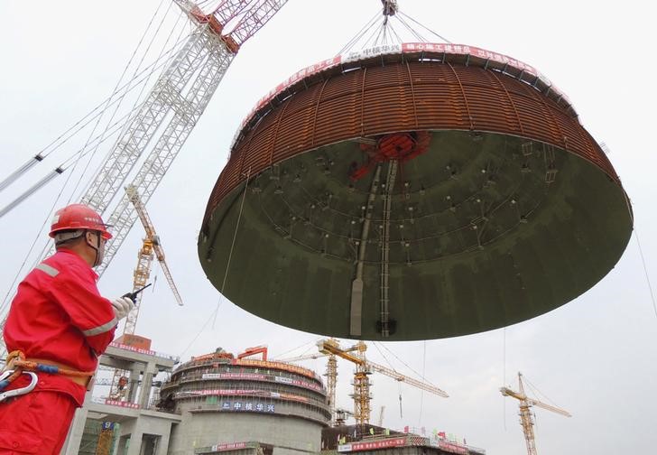 © Reuters. Рабочий следит за установкой крыши энергоблока на китайской атомной электростанции Тяньвань