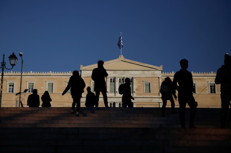 © Reuters. People walk in front of the parliament building in Athens