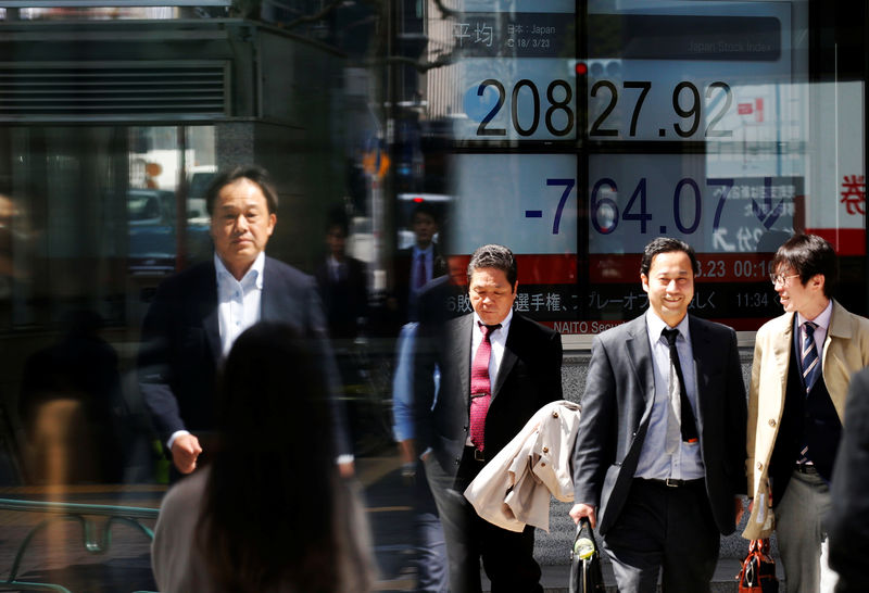 © Reuters. People walk past an electronic board showing Japan's Nikkei average outside a brokerage in Tokyo