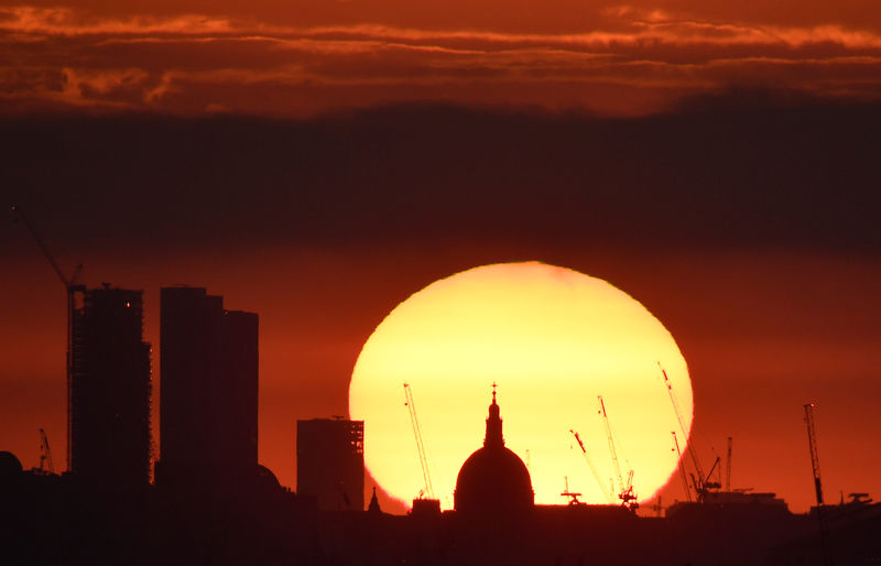 © Reuters. The dome of St Paul's Cathedral and construction cranes are silhouetted by the rising sun at dawn in London