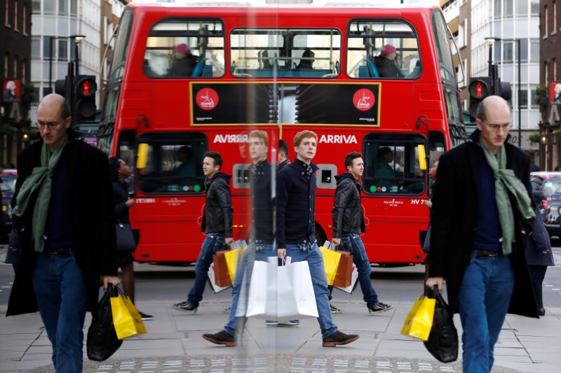 © Reuters. FILE PHOTO: Shoppers are reflected in a window as they carry bags along Oxford street during the final weekend of shopping before Christmas in London