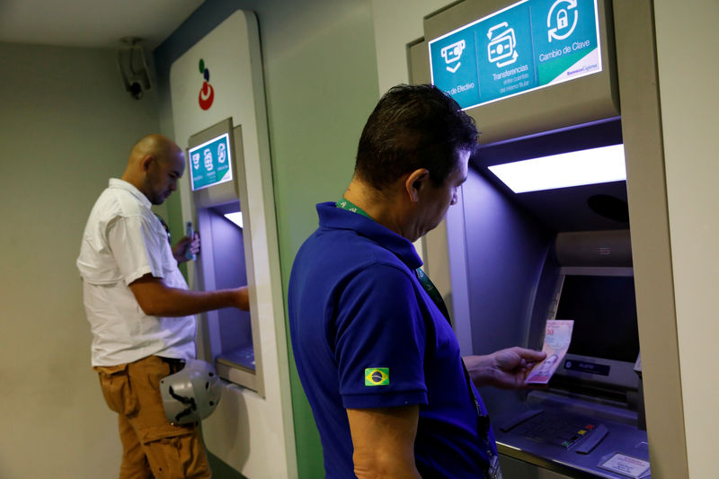 © Reuters. Un hombre mira un nuevo billete de 10 bolívares soberanos en un cajero automático en una oficina del banco Banesco en Caracas.