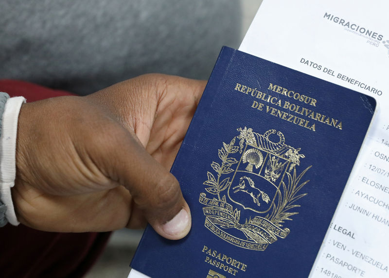 © Reuters. Un migrante venezolano sostiene su pasaporte en una fila para obtener un permiso de residencia temporal en Lima, Perú