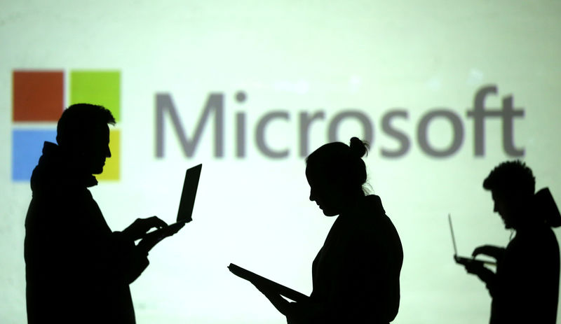 © Reuters. Силуэты пользователей с ноутбуками на фоне логотипа Microsoft