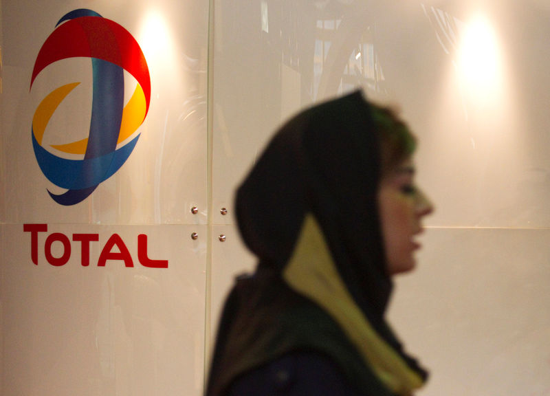 © Reuters. FILE PHOTO: A woman walks past Total's stand at the 15th International Oil, Gas, Refining & Petrochemical Exhibition in Tehran