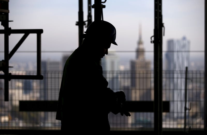 © Reuters. The Palace of Culture is seen behind a worker at a construction site in Poland October 2, 2015.