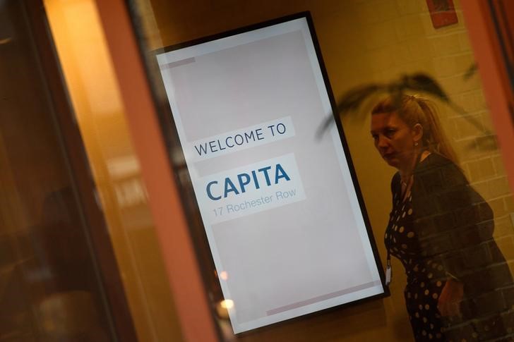 © Reuters. FILE PHOTO: A woman walks past a sign welcoming visitors to Capita offices in London