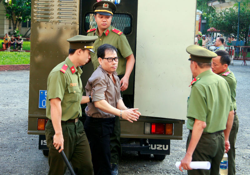 © Reuters. U.S. citizen James Nguyen is escorted by police to a court before his trial in Ho Chi Minh city