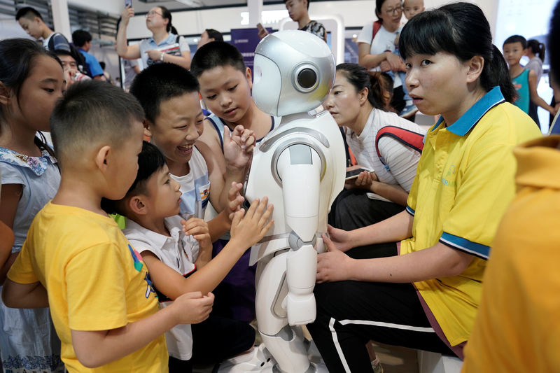 © Reuters. Children play with an iPal robot at Avatarmind's booth at the WRC in Beijing